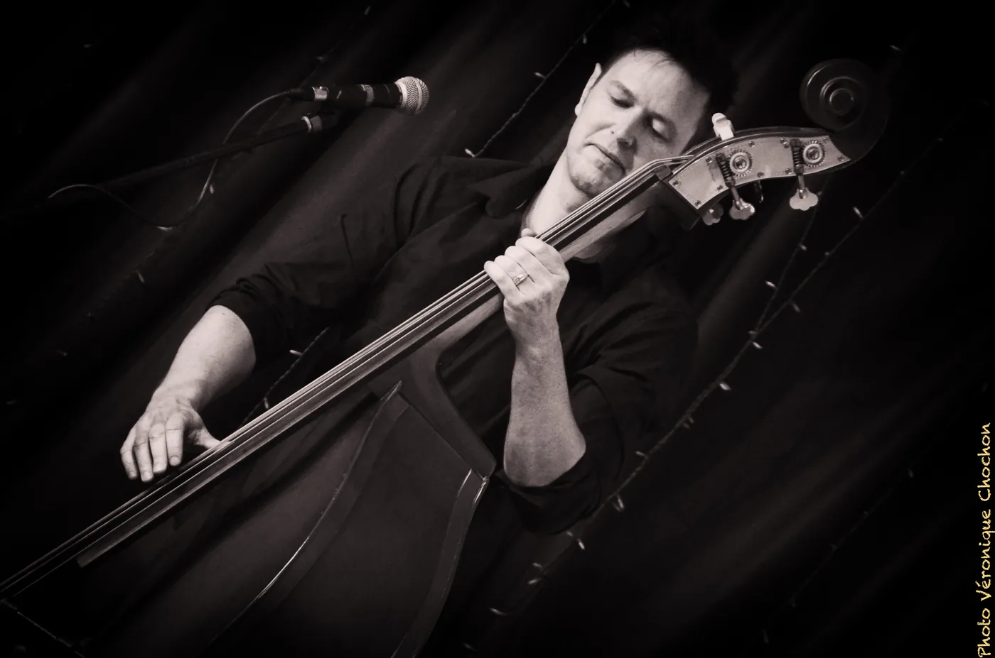 Alexandre Roux on double bass in concert, black and white, eyes closed on a pizzicato